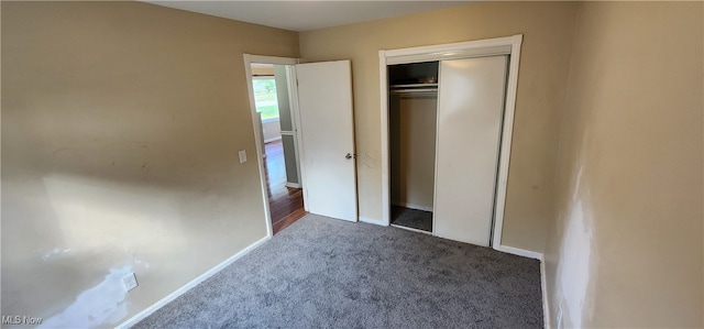 unfurnished bedroom with dark carpet and a closet