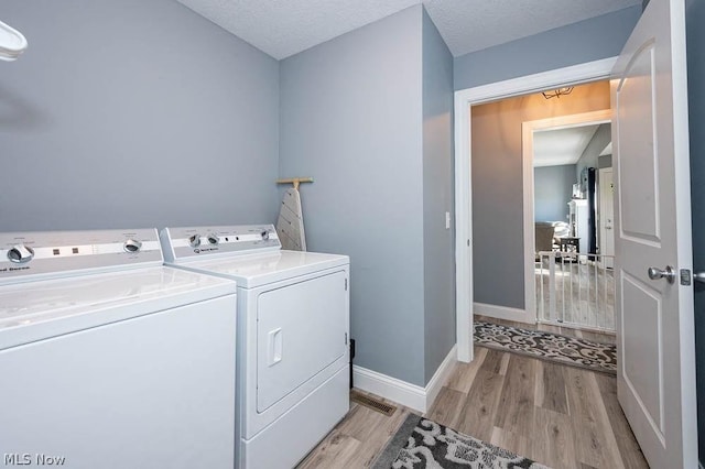 clothes washing area featuring light hardwood / wood-style flooring, a textured ceiling, and independent washer and dryer