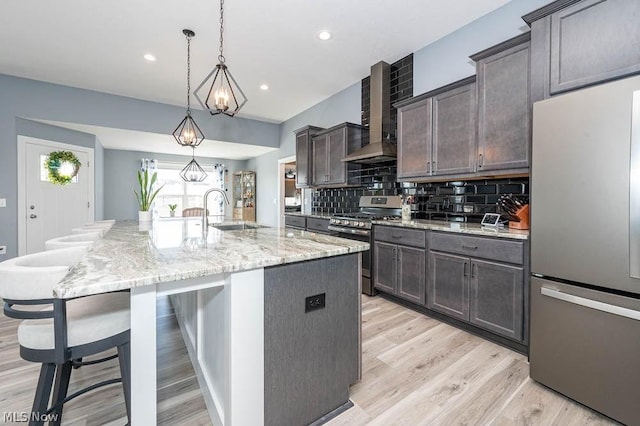 kitchen with light stone countertops, stainless steel appliances, backsplash, a large island with sink, and pendant lighting