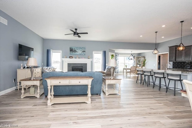 living room with ceiling fan, sink, and light hardwood / wood-style floors