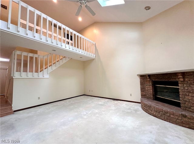 unfurnished living room with ceiling fan, a fireplace, and lofted ceiling with skylight