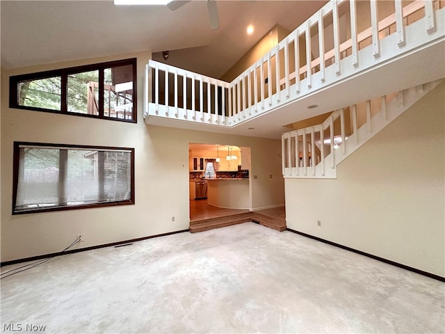 unfurnished living room with a towering ceiling, ceiling fan, and carpet floors