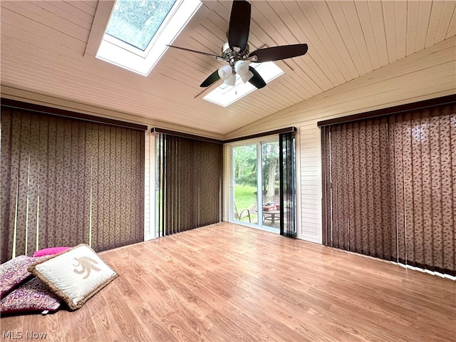 empty room with vaulted ceiling with skylight, wooden ceiling, hardwood / wood-style flooring, and ceiling fan