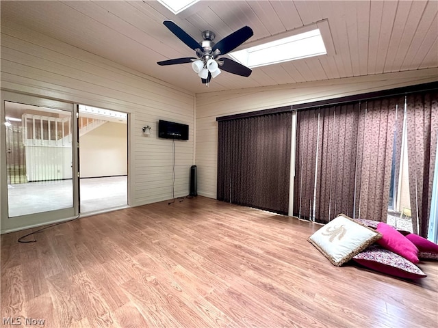 unfurnished bedroom featuring ceiling fan, access to exterior, light hardwood / wood-style flooring, and vaulted ceiling with skylight