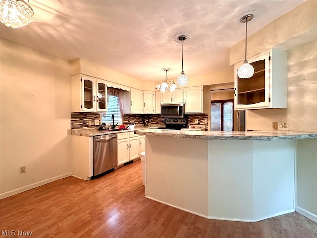 kitchen featuring decorative light fixtures, kitchen peninsula, stainless steel appliances, hardwood / wood-style flooring, and white cabinetry