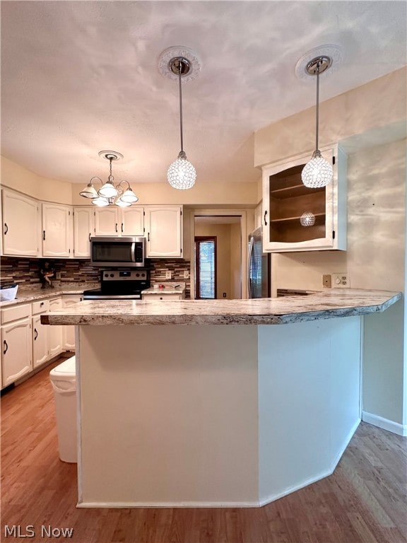 kitchen with hardwood / wood-style floors, stainless steel appliances, white cabinets, and decorative light fixtures