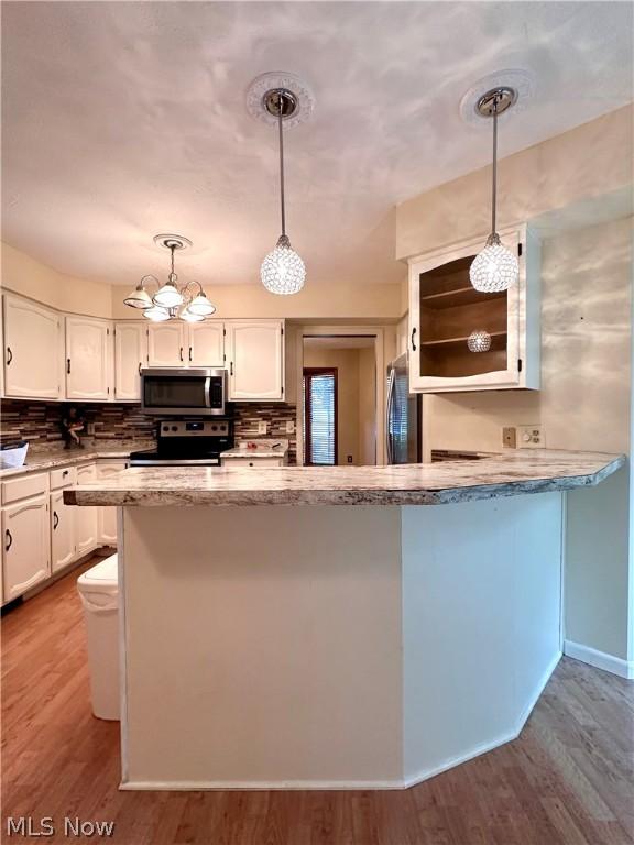 kitchen featuring decorative backsplash, white cabinets, wood finished floors, and stainless steel appliances