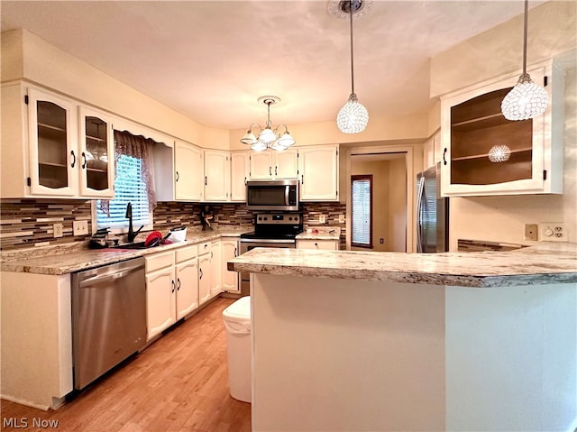 kitchen featuring stainless steel appliances, white cabinetry, light hardwood / wood-style flooring, and tasteful backsplash