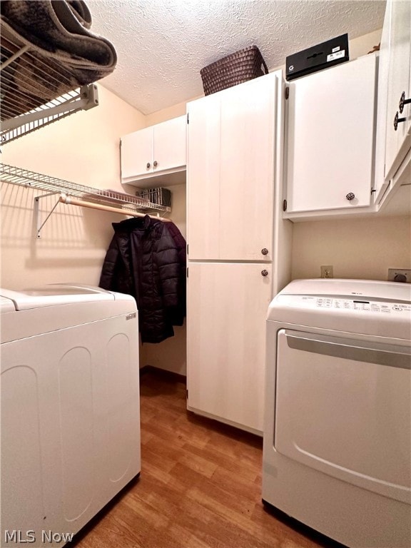 laundry area with cabinets, a textured ceiling, separate washer and dryer, and wood-type flooring