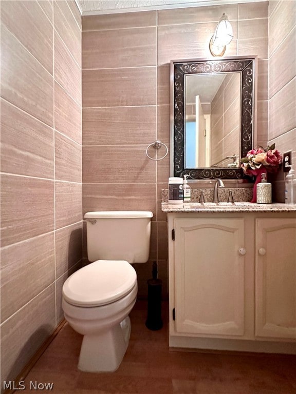 bathroom featuring vanity, toilet, and tile walls