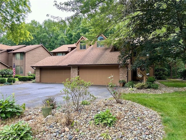 view of front facade featuring aphalt driveway, brick siding, a garage, and roof with shingles