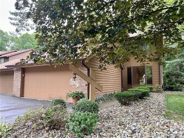 view of front of property featuring aphalt driveway, brick siding, and an attached garage