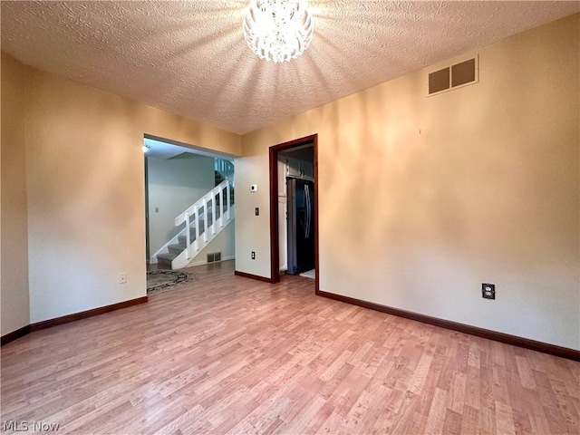 spare room featuring stairway, wood finished floors, visible vents, and baseboards