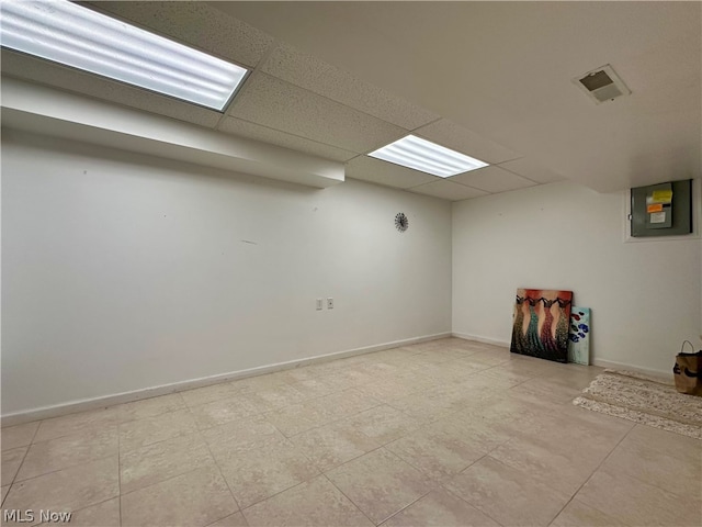 basement with a paneled ceiling and light tile floors