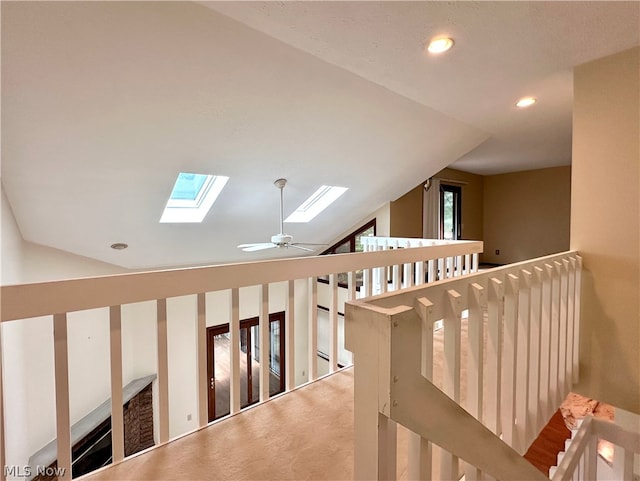 interior space featuring carpet flooring, lofted ceiling with skylight, and ceiling fan