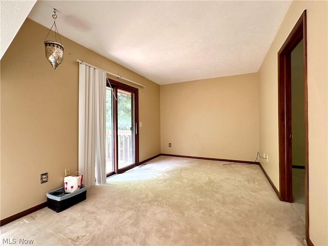 spare room with baseboards, light carpet, and a textured ceiling