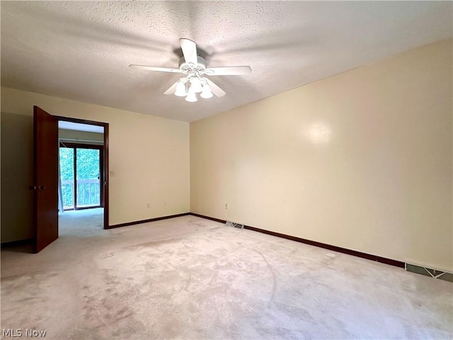 unfurnished room featuring baseboards, light carpet, a textured ceiling, and ceiling fan