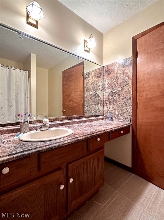 bathroom with tile flooring, vanity, and a textured ceiling