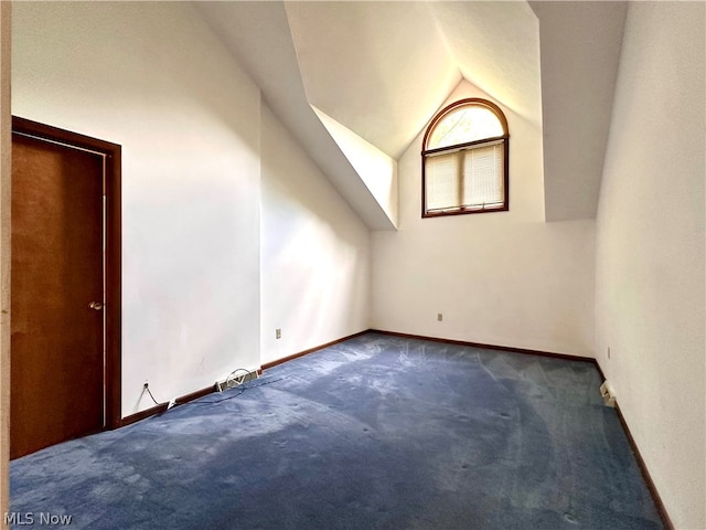 additional living space with lofted ceiling and dark colored carpet