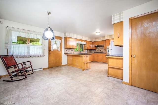 kitchen with kitchen peninsula, a kitchen breakfast bar, decorative backsplash, sink, and decorative light fixtures