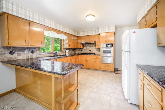 kitchen with kitchen peninsula, sink, white fridge, and stainless steel gas stovetop