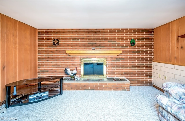 unfurnished living room featuring brick wall, carpet floors, and wood walls