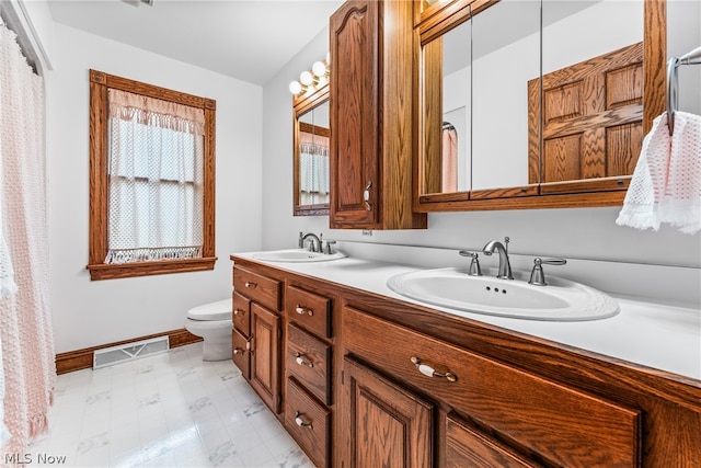 bathroom with vanity with extensive cabinet space, dual sinks, toilet, and tile flooring