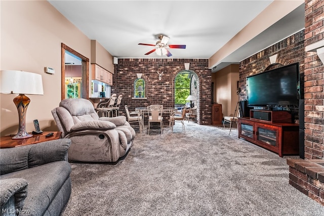 living room with ceiling fan, carpet floors, and brick wall