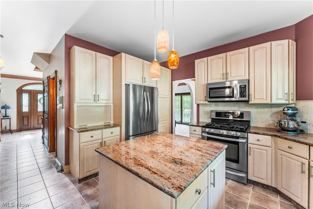 kitchen featuring a center island, hanging light fixtures, appliances with stainless steel finishes, tile floors, and backsplash