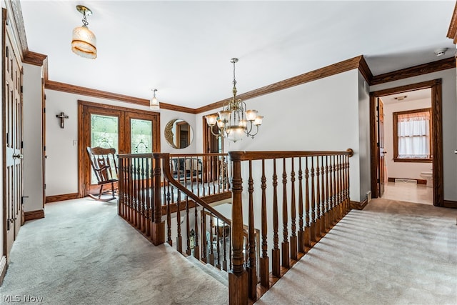 hallway with a notable chandelier, carpet floors, and crown molding