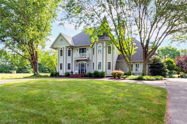 view of front of property featuring a front yard and a balcony