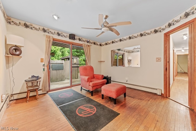 living area with baseboard heating, ceiling fan, and light hardwood / wood-style flooring