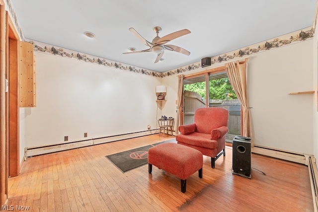 living area featuring baseboard heating, ceiling fan, and hardwood / wood-style floors