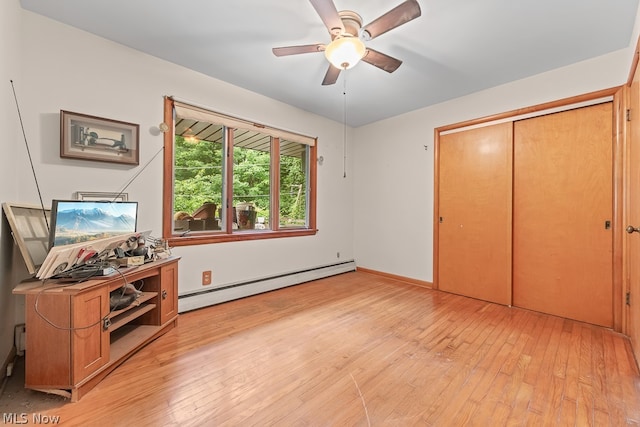 bedroom featuring ceiling fan, a closet, a baseboard heating unit, and light hardwood / wood-style flooring