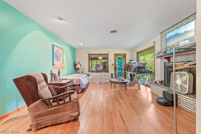 bedroom featuring a fireplace with raised hearth, light wood-type flooring, and visible vents