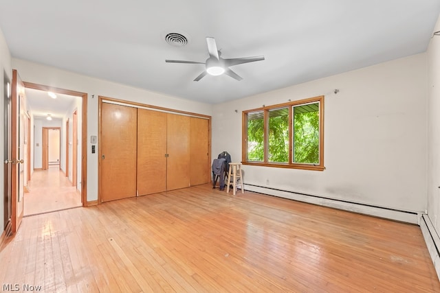 unfurnished bedroom featuring a baseboard heating unit, ceiling fan, a closet, and light wood-type flooring