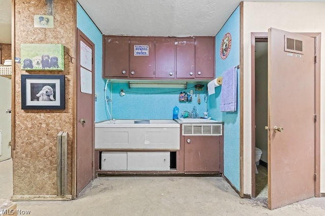 kitchen with visible vents, a sink, a textured ceiling, and unfinished concrete floors