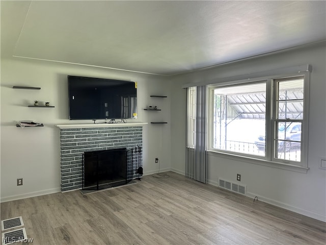 unfurnished living room featuring a fireplace, wood-type flooring, and plenty of natural light