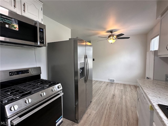 kitchen with appliances with stainless steel finishes, white cabinetry, ceiling fan, and light hardwood / wood-style flooring