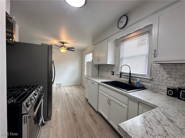 kitchen with double oven range, sink, backsplash, light hardwood / wood-style floors, and ceiling fan