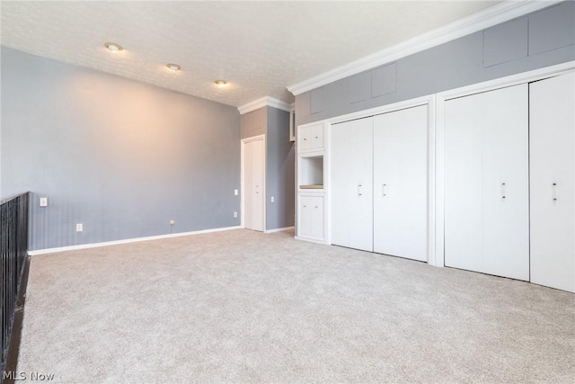 unfurnished bedroom with carpet, a textured ceiling, and two closets