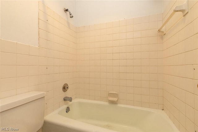 bathroom featuring tiled shower / bath, tile walls, and toilet