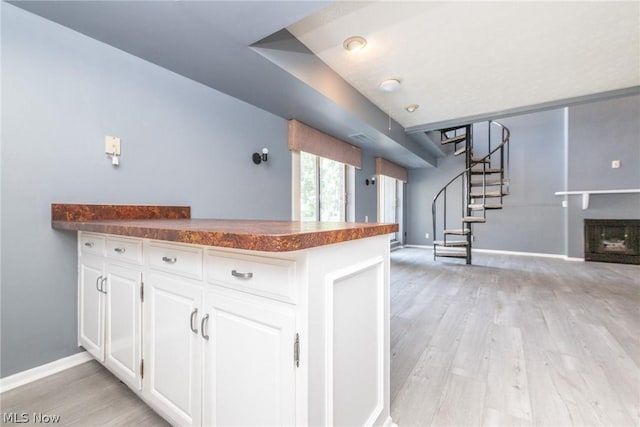 kitchen with kitchen peninsula, white cabinetry, and light hardwood / wood-style floors