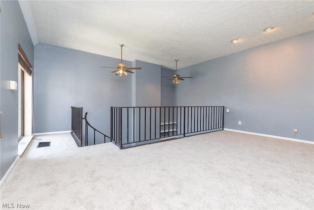 carpeted spare room with ceiling fan and a textured ceiling