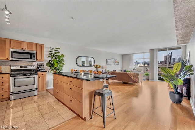 kitchen featuring decorative backsplash, light hardwood / wood-style floors, stainless steel appliances, and a breakfast bar area