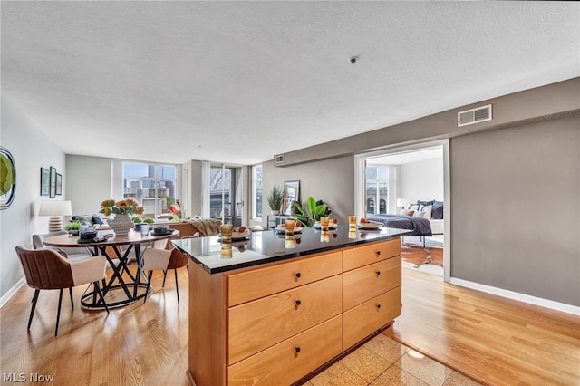 kitchen featuring light brown cabinets, a center island, a textured ceiling, and light wood-type flooring