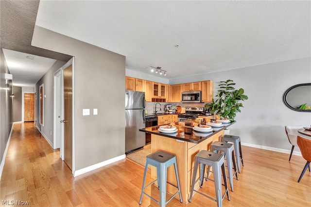 kitchen with a breakfast bar, sink, stainless steel appliances, and light hardwood / wood-style flooring