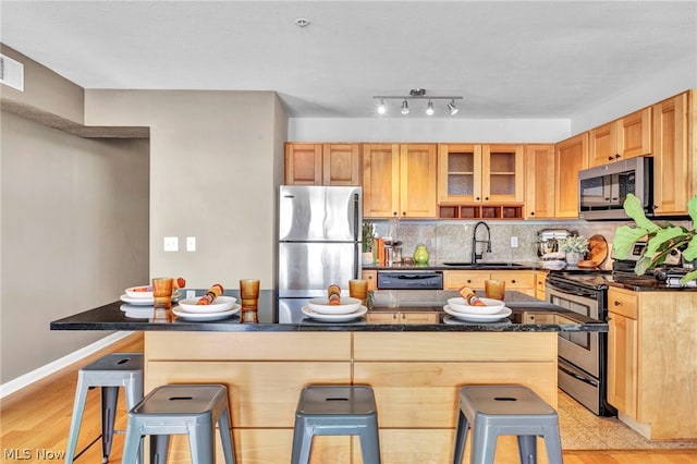 kitchen featuring sink, a breakfast bar, light hardwood / wood-style floors, and appliances with stainless steel finishes