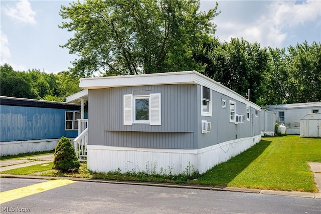 view of front of home featuring an AC wall unit and a front lawn