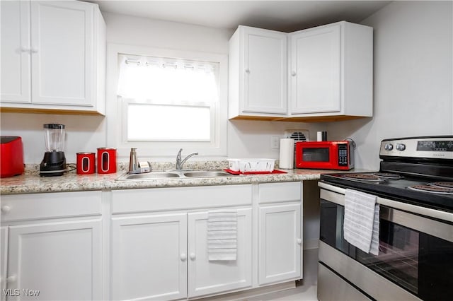 kitchen with stainless steel electric range oven, white cabinets, a sink, and light countertops